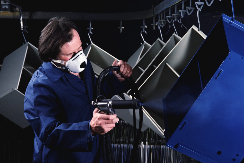 man using powder coating sprayer to paint industrial equipment